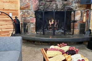 A fireplace with a fire, surrounded by stone walls and a wooden floor.