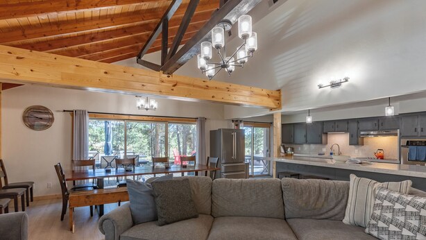 A modern kitchen with a built-in oven, a dining area with a wooden table and chairs, and a large window providing natural light.