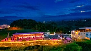 Un hotel con un edificio amplio, una zona de estacionamiento y vistas a una ciudad al fondo.