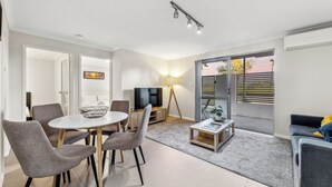 Una sala de estar moderna con comedor, televisor y balcón con vistas.