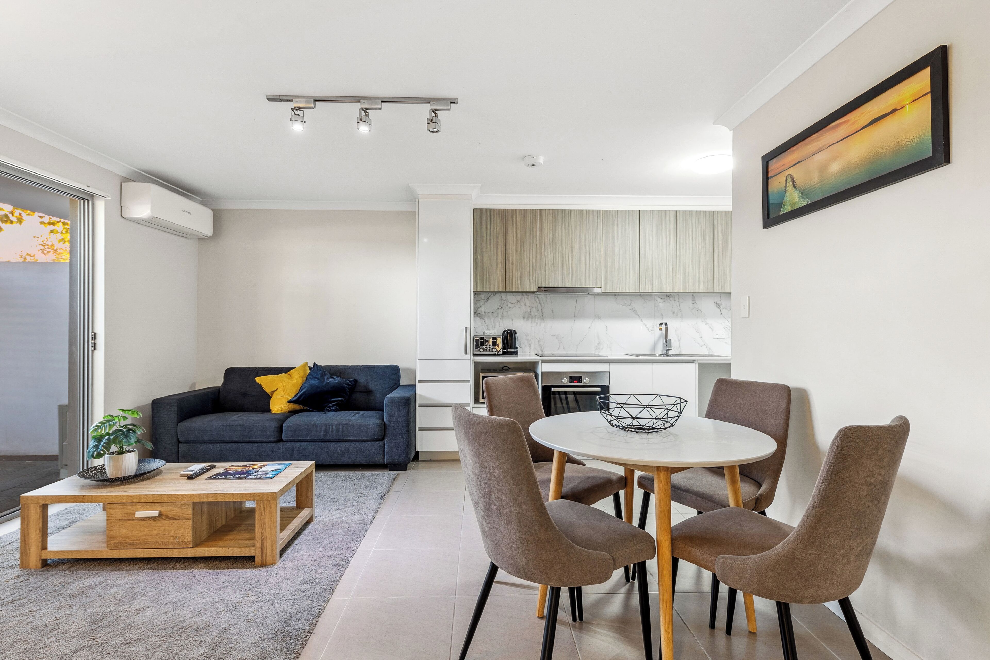 A modern living room with a sofa, coffee table, and dining area.