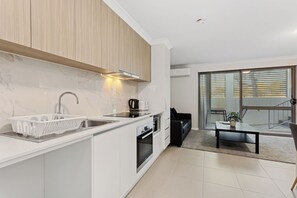 A modern kitchen with a built-in oven, a sink, and a coffee maker. - Yaran Suites (Rockingham)