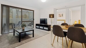 Una sala de estar moderna con comedor, televisor y una escalera que sube a un piso superior.