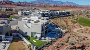 A modern residential complex with multiple buildings, a swimming pool, and a well-maintained lawn.
