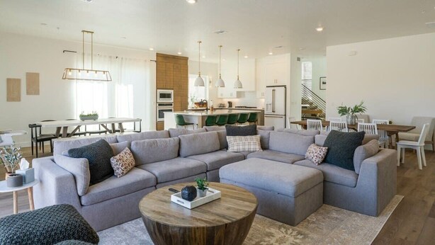 A spacious living room with a large grey sectional sofa, a wooden coffee table, and a dining area with a white table and chairs. - Birdie On The 8th | Private Pool/Hot Tub (Washington)