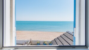 A view through a window of a beach with a clear sky. - Wave Cottage -  seaside cottage right on the beach by Bloom Stays (Sandgate)