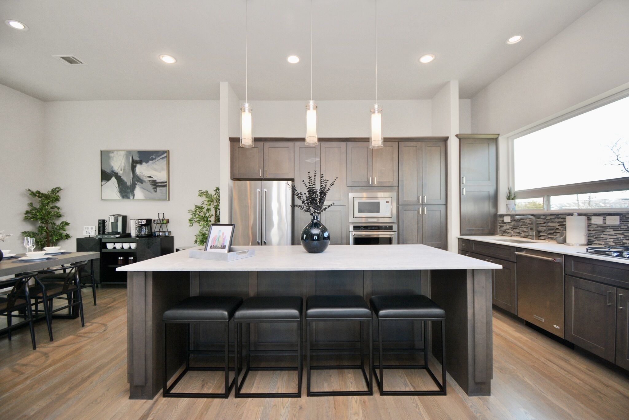 A modern kitchen with a large island, stainless steel appliances, and pendant lighting.