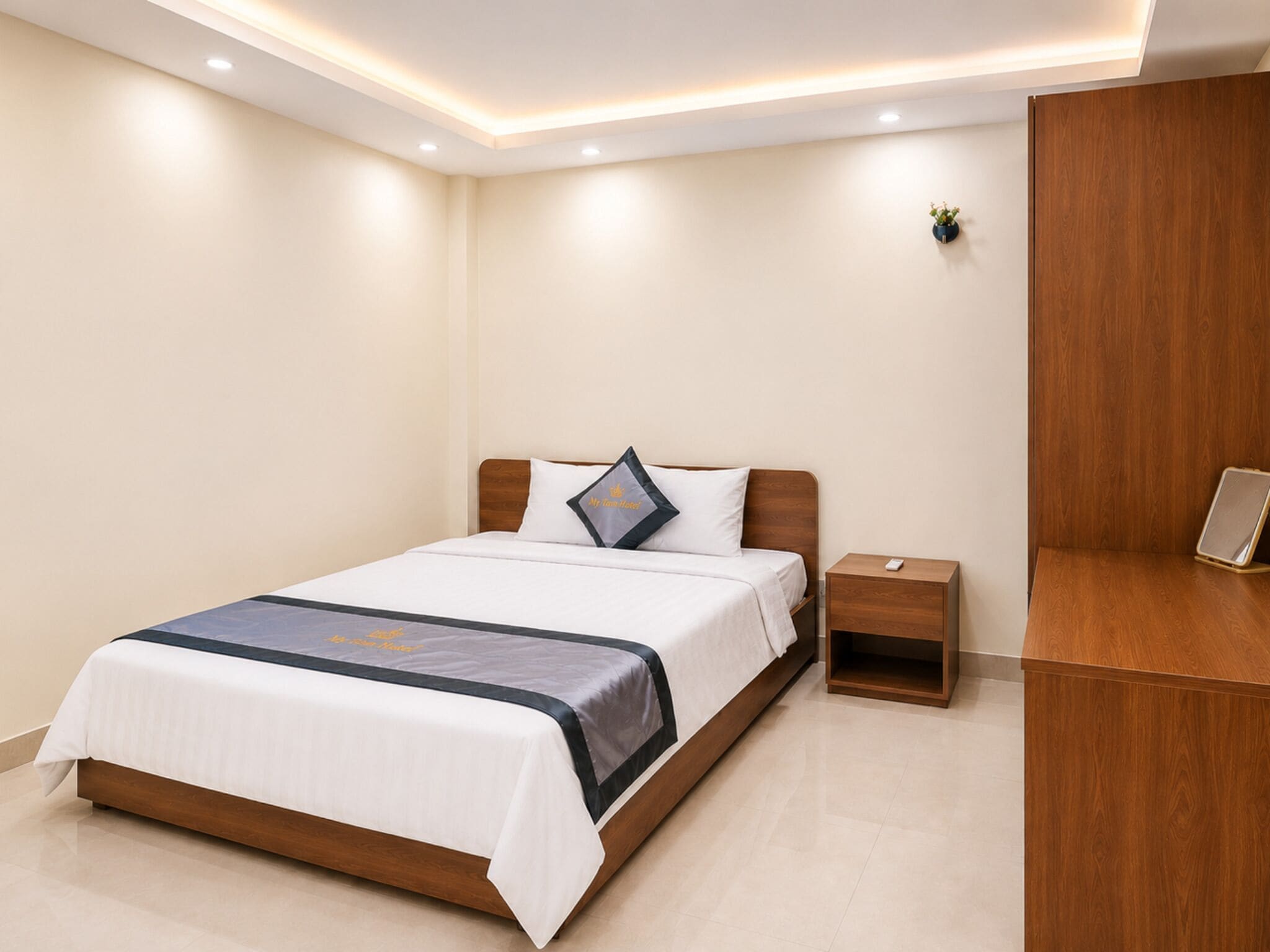 A neatly arranged bedroom with a bed, bedside table, and a wooden wardrobe.
