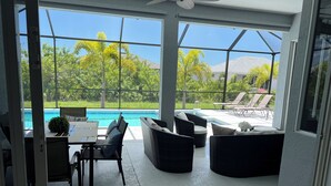 Une chambre moderne avec vue sur une piscine, dotée de mobilier d’extérieur et d’un espace repas.