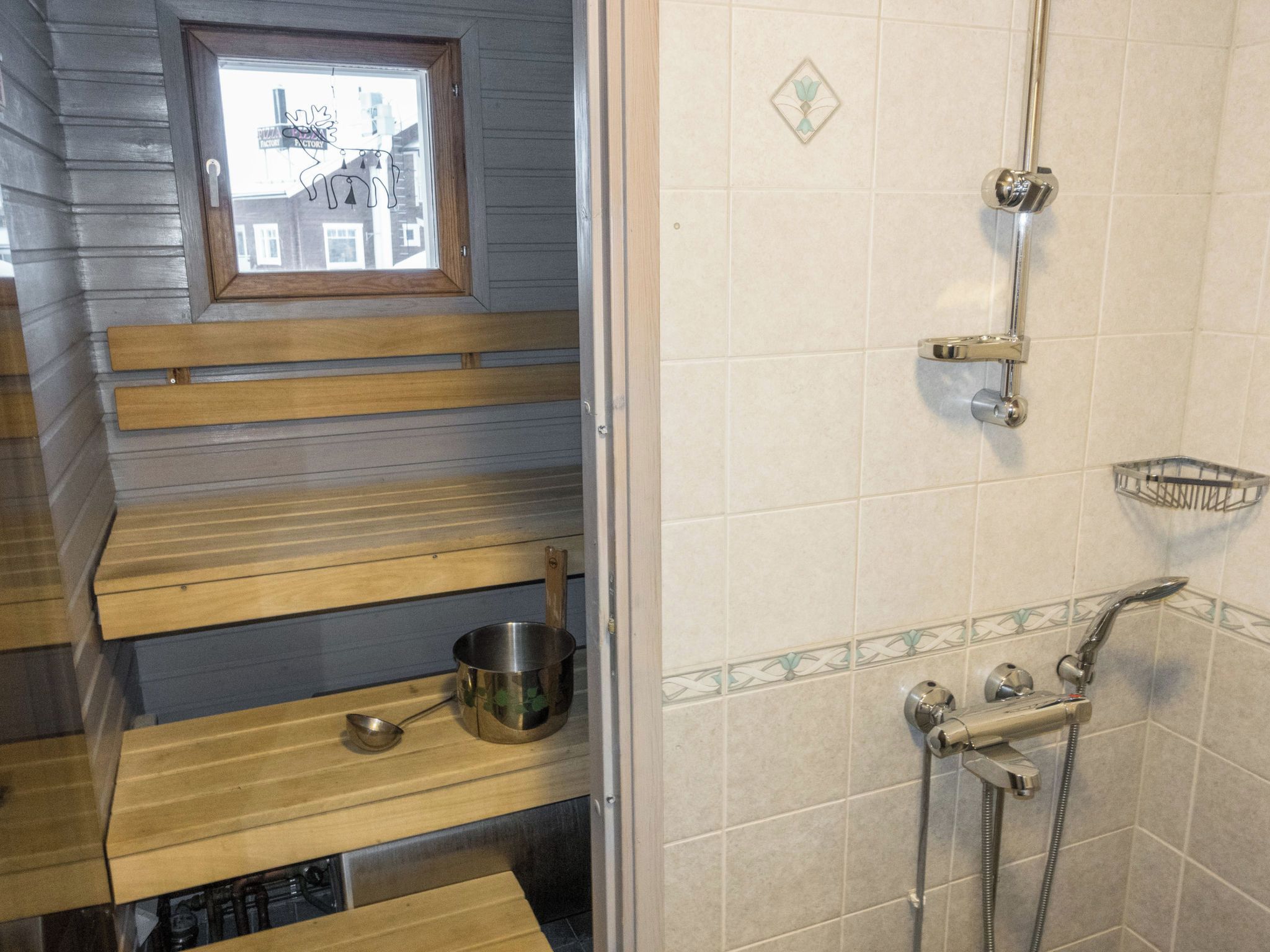 Un bagno con doccia, lavandino e una finestra vista edifici.