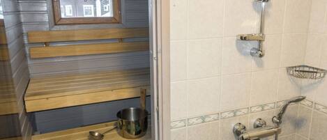 Un bagno con doccia, lavandino e una finestra vista edifici.