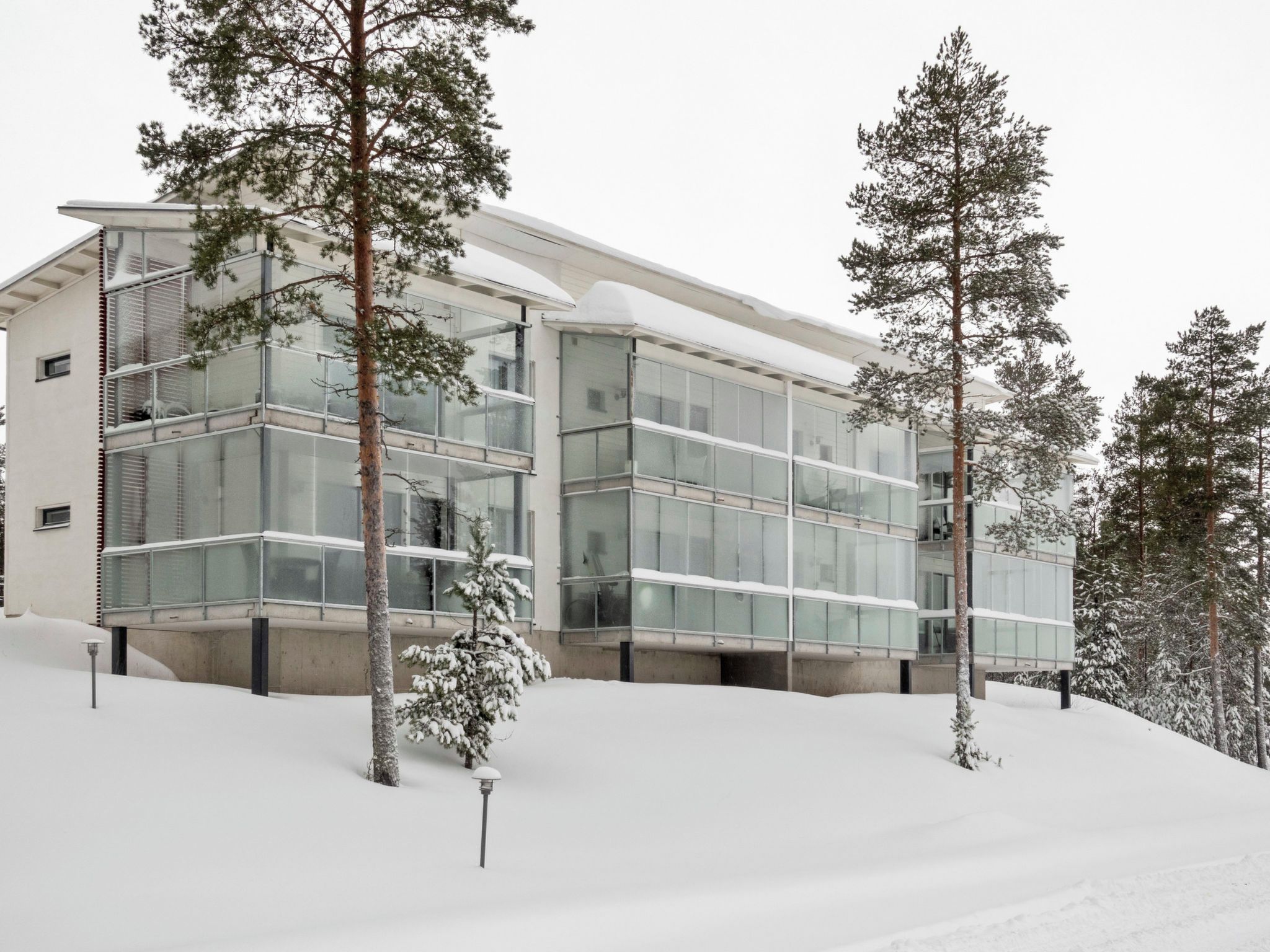 Un edificio moderno con grandes ventanales y un paisaje cubierto de nieve.
