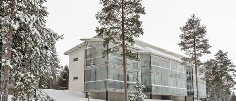 En moderne bygning med en glasfacade omgivet af sneklædte træer.
