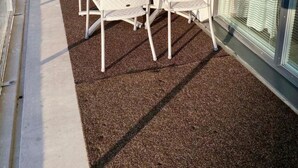 An outdoor patio with a table and chairs, a glass door, and a view of the surrounding area.