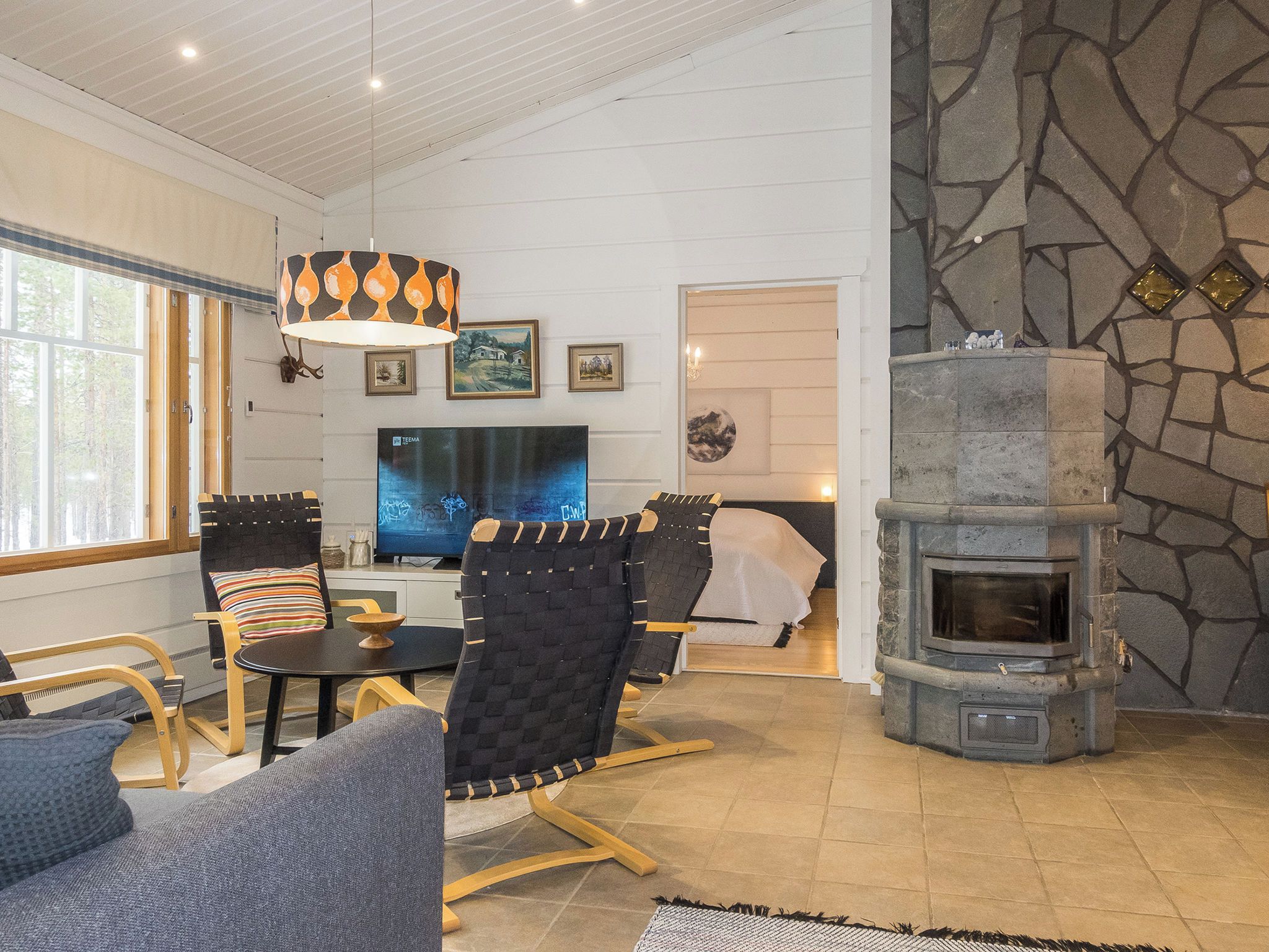 A cozy living room with a stone fireplace, comfortable seating, and a television.