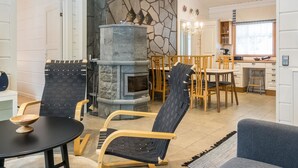 Une cuisine moderne avec un mur en pierre, des chaises en bois, une table à manger et un four encastré.