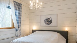 Une chambre à coucher avec un lit, un lustre, une fenêtre avec des rideaux et un tableau accroché au mur.