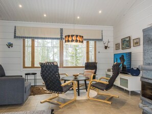 A cozy living room with a fireplace, a television, and a dining area with chairs and a table.