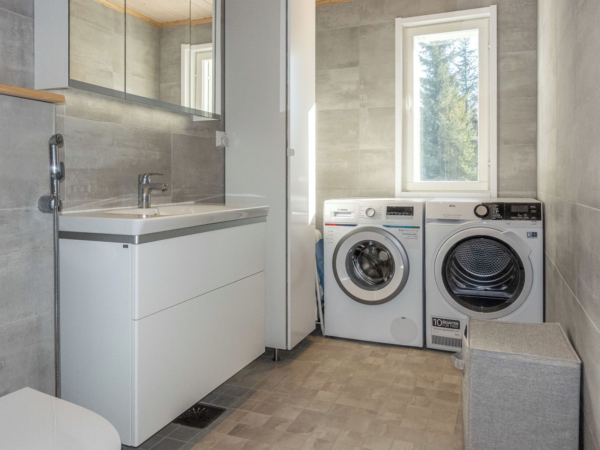 Ein modernes Badezimmer mit Waschbecken, Spiegel und zwei Waschmaschinen.