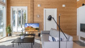 Una sala de estar moderna con un televisor grande, un sofá, una mesa de centro y una lámpara de pie.