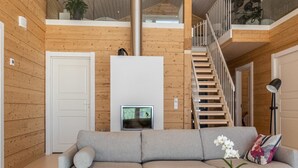 Una sala de estar moderna con un sofá gris, una mesa de centro y una escalera que lleva a un nivel superior.