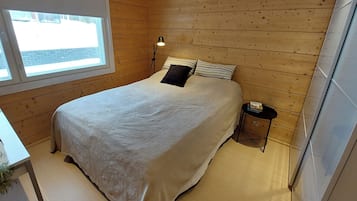 A bedroom with a bed, a nightstand, a lamp, and a window.