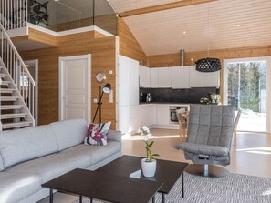Un interior modern amb una escala, un sofà, una taula de cafè i una zona de cuina.