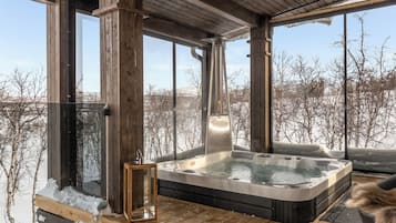 Eine Holzterrasse mit Whirlpool und einer Glastür.