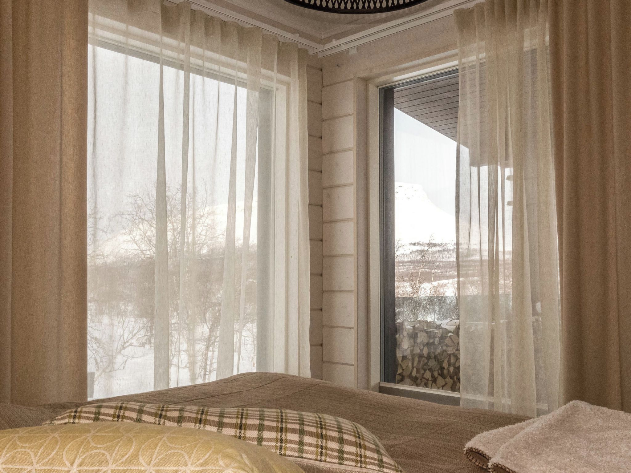 Una camera da letto con un'ampia finestra, un letto con copripiumino decorato e vista su un paesaggio innevato.