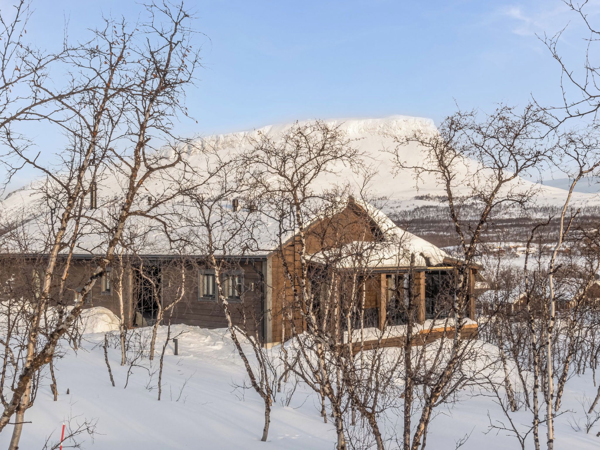 Paesaggio innevato con un edificio in legno e alberi spogli.