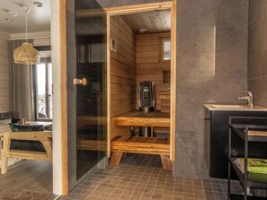 Un sauna doté d’une porte en verre, de bancs en bois et d’un appareil de chauffage en métal.