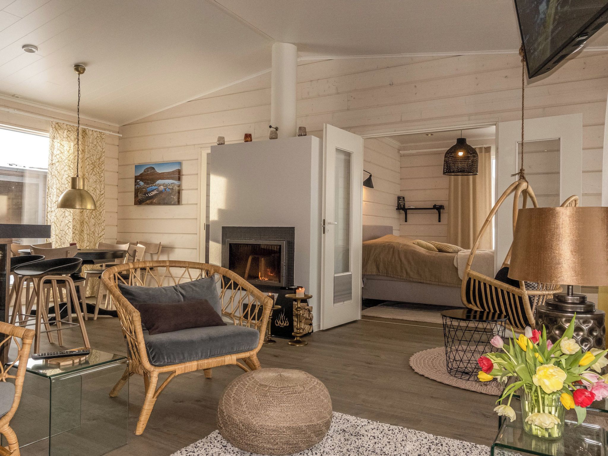 A cozy living room with a fireplace, wicker furniture, and a dining area with chairs and a table.
