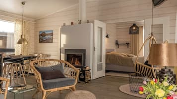 A cozy living room with a fireplace, wicker furniture, and a dining area with chairs and a table.