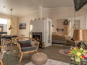 A cozy living room with a fireplace, wicker furniture, and a dining area with chairs and a table. - Haltinmalla by Interhome (Enontekiö)
