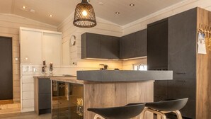 Een moderne keuken met donkere kastjes, een houten eiland en barstoelen.