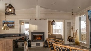 Een ruime woonkamer met een open haard, rieten stoelen en een houten bar.