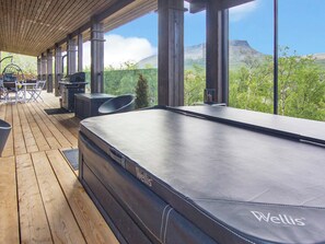 Eine Holzterrasse mit Whirlpool, Gartenmöbeln und einem schönen Ausblick.