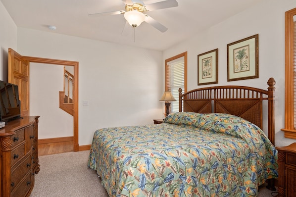 A bedroom with a bed, a dresser, a ceiling fan, and framed pictures on the wall. - Soundbreeze Sunset: Golf and sound views, hot tub, dog friendly, elevator. (Nags Head)