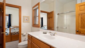 Un baño con tocador de madera, un espejo grande, un lavamanos y un inodoro.