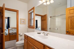 A bathroom with a wooden vanity, a large mirror, a sink, and a toilet.
