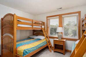 A bunk bed with a ladder, a bedside table with a lamp, and a window with blinds. - Soundbreeze Sunset: Golf and sound views, hot tub, dog friendly, elevator. (Nags Head)