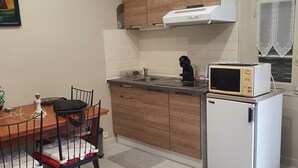Kompakti keittiö, jossa on puukaapit, mikroaaltouuni ja pieni jääkaappi.