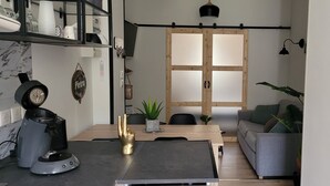 Un espacio habitable compacto con una mesa de comedor, un sofá, una cafetera y una puerta corredera.