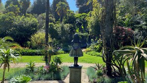 A statue of a girl in a garden with various plants and trees. - The Wadham (Weymouth)