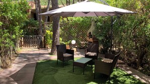 An outdoor patio area with wicker furniture and a large umbrella. - Pinus Village 170m from the beach (Santa Margherita di Pula)