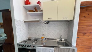 A compact kitchen with a gas stove, oven, and built-in washing machine. - Pinus Village 170m from the beach (Santa Margherita di Pula)