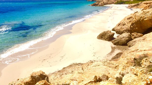 A beach with clear turquoise water, sandy shore, and rocky terrain. - Pinus Village 170m from the beach (Santa Margherita di Pula)