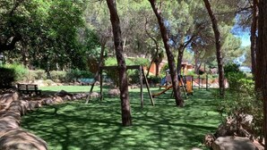 A park with a playground, benches, and a grassy area surrounded by trees and rocks. - Pinus Village 170m from the beach (Santa Margherita di Pula)