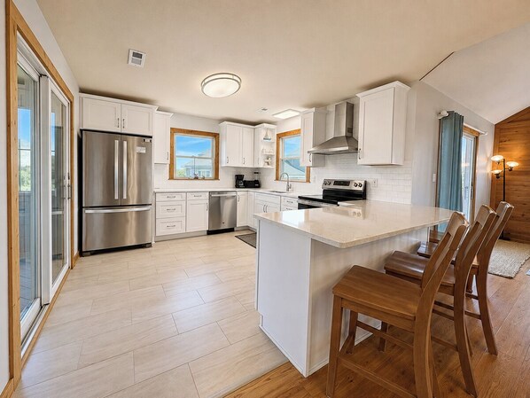 A modern kitchen with a central island, stainless steel appliances, and a large window.