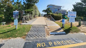 A private beach access area with a wooden walkway leading to a pool, marked with 'NO PARKING' and 'PRIVATE NO PARKING' signs. - Our Legacy - Dog Friendly Oceanside 4 BR Cottage with Community Pool access (Duck)